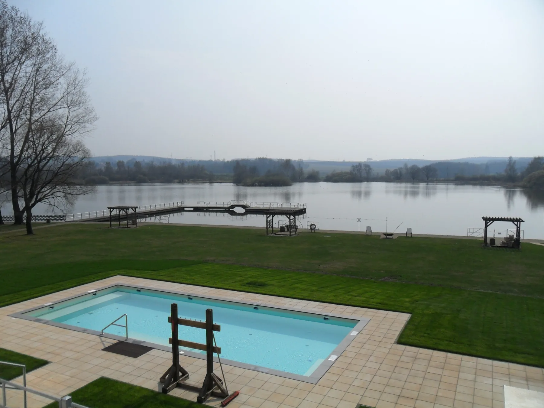 Außenpool und Steg, dahinter der Teich im Frühling