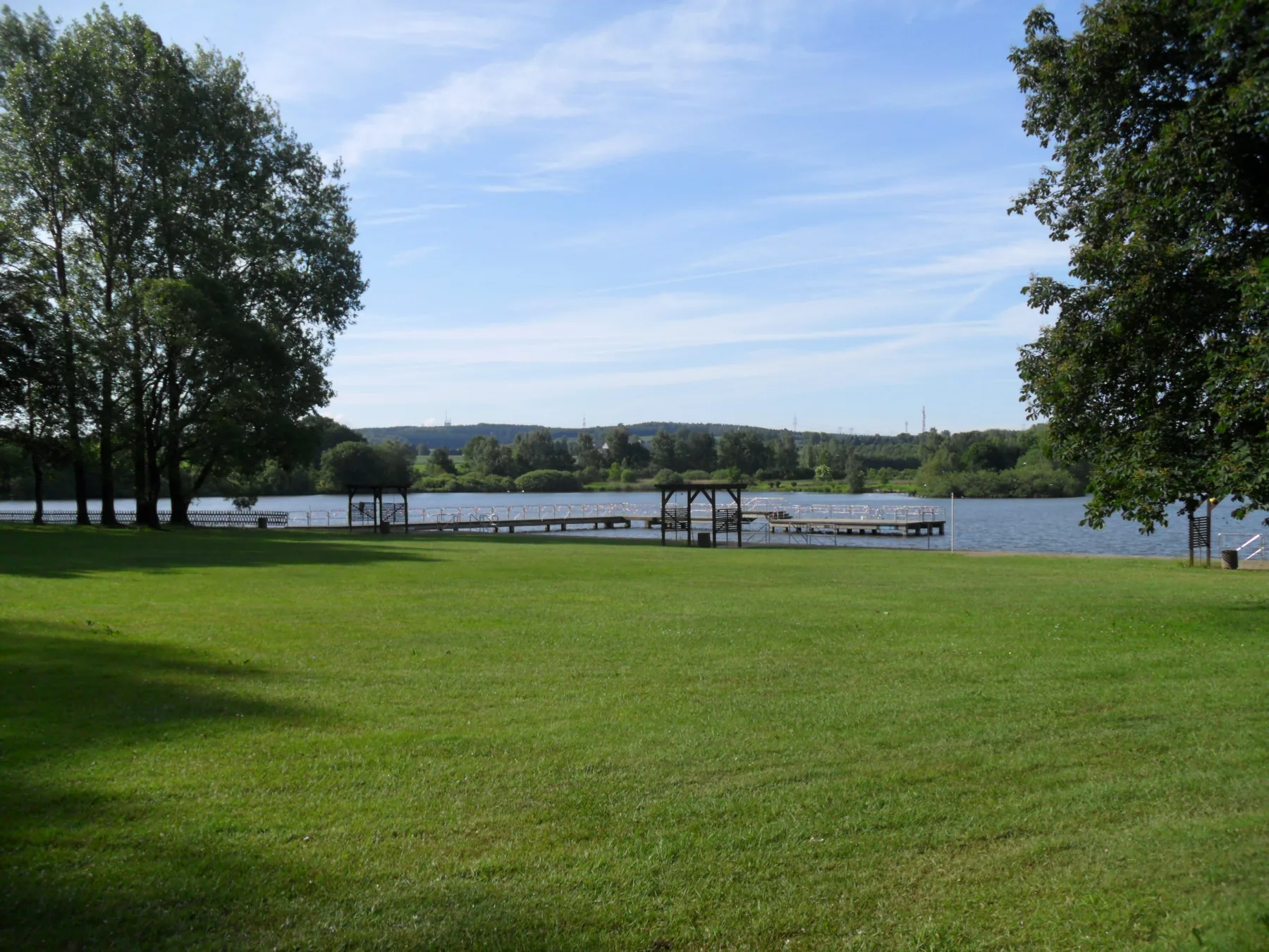 Rasenfläche mit Steg und Teich im Hintergrund