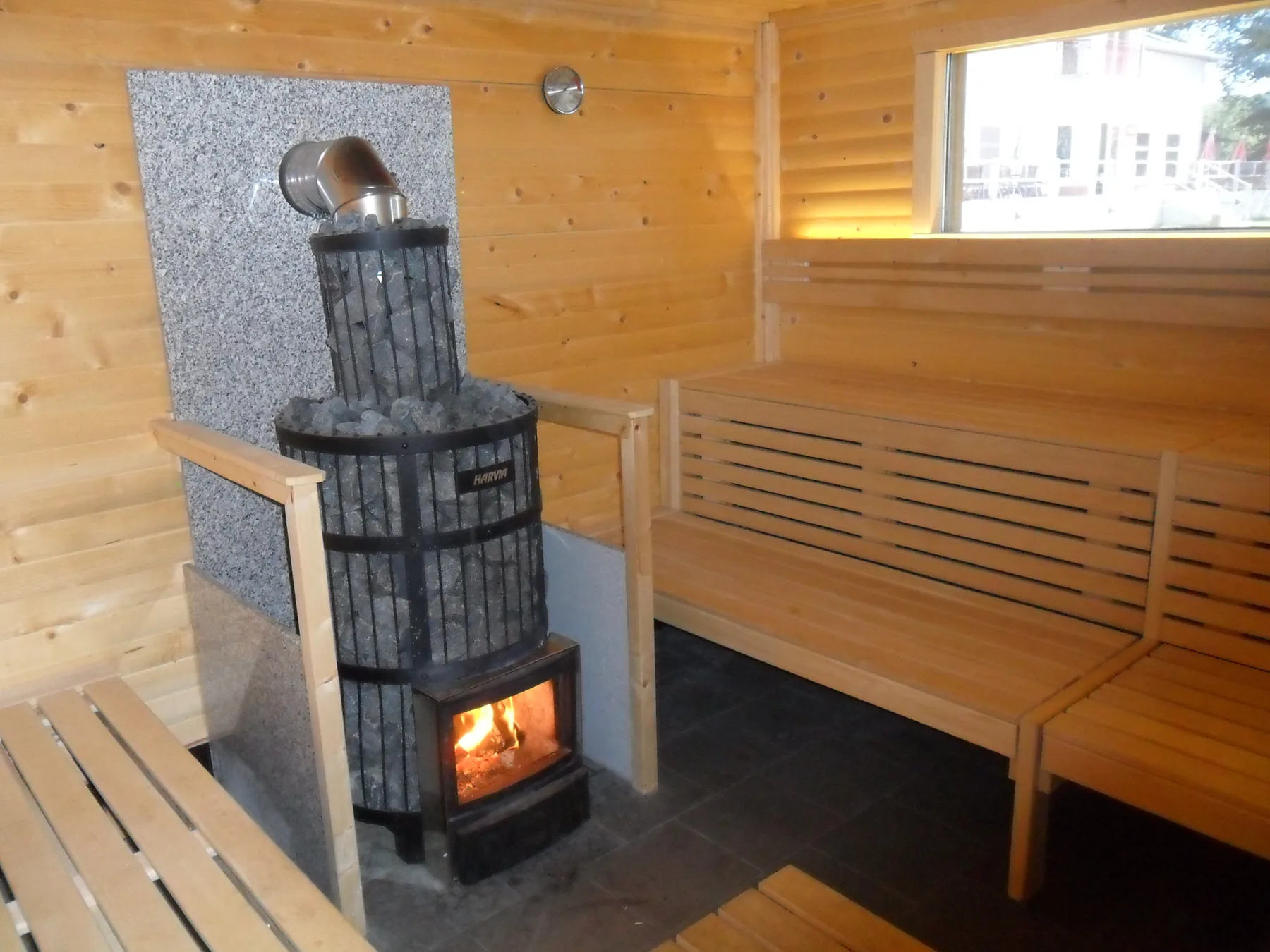 Finnische Sauna mit hellem Holz und Kaminofen