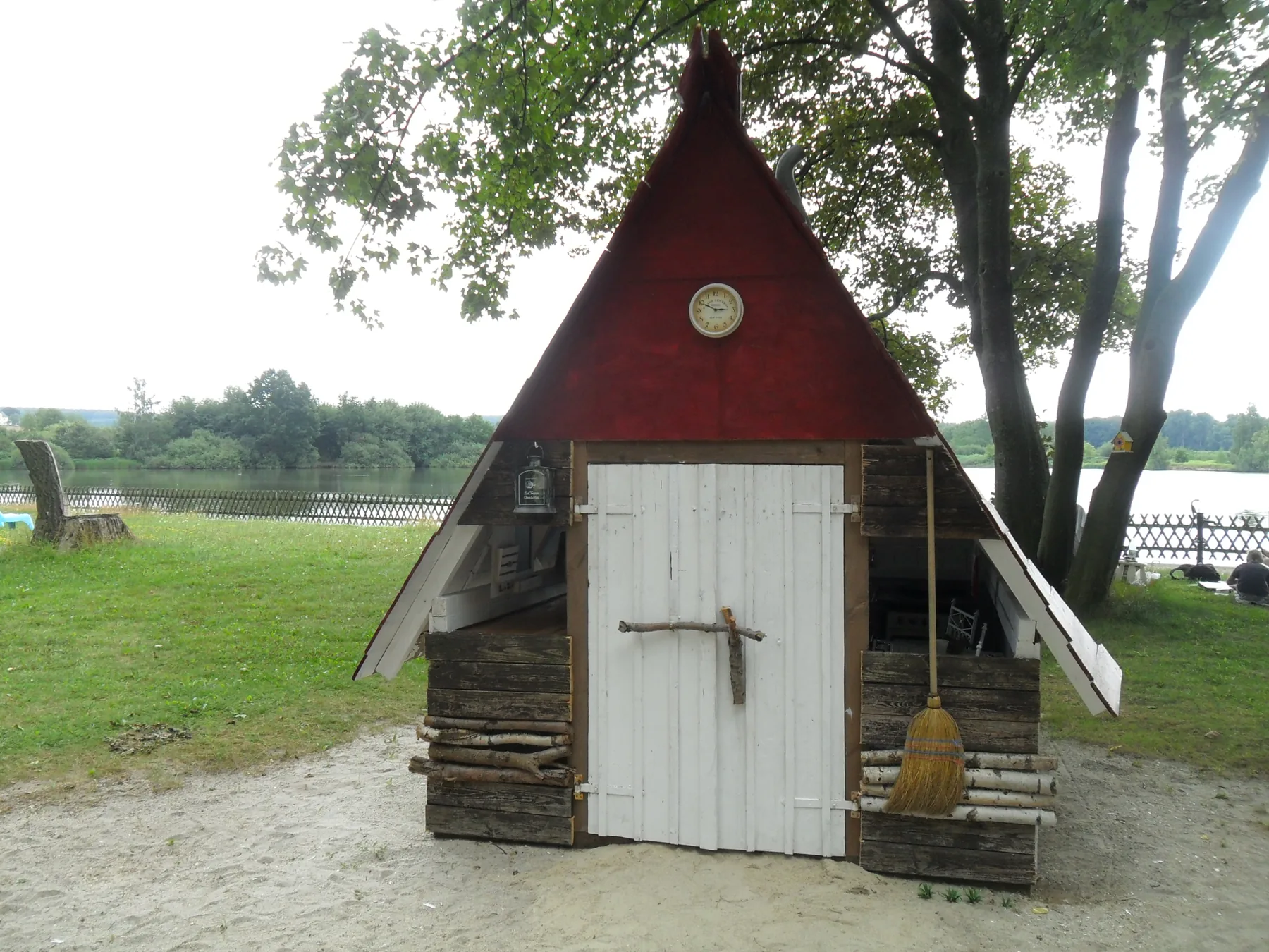 Holzhäuschen mit rotem Spitzdach am Rand der Wiese
